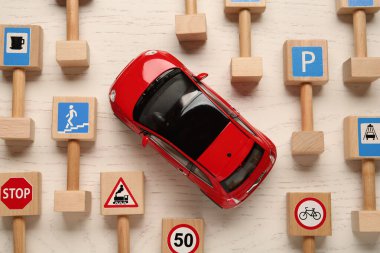 Birçok farklı minyatür yol tabelaları ve beyaz ahşap masa üzerinde düz bir araba. Sürücü kursu