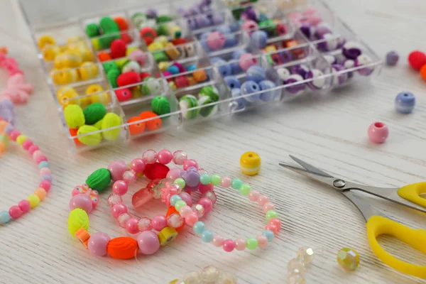 Beyaz ahşap masada el yapımı güzel mücevherler ve malzemeler.