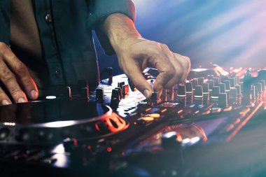 DJ, gece kulübünde modern konsol karıştırıcısında müzik yaratıyor.