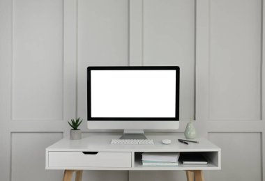 Modern bilgisayar, dekor ve ofis malzemeleri, pervazların yanındaki beyaz ahşap masada.