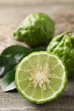 Taze olgun bergamot meyveleri ve ahşap masada yeşil yapraklar, yakın plan.
