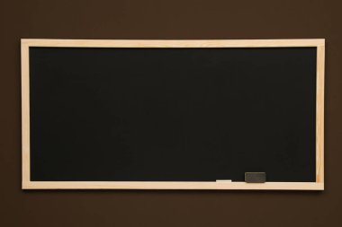 Kahverengi duvarda asılı temiz siyah karatahta