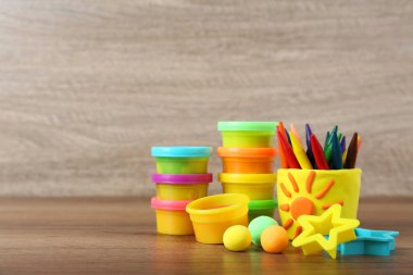 Aletlerle ve ahşap masanın üzerinde renkli kalemlerle oynanan parlak oyun hamuru. Metin için boşluk