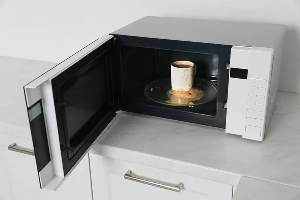 キッチンでコーヒーカップと汚れた電子レンジ — ストック写真