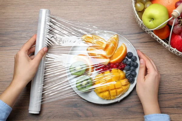 Frau Legt Plastikfolie Über Teller Mit Frischem Obst Und Beeren — Stockfoto