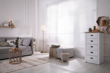 Oturma odasında rahat gri kanepe, kanepe ve pencerenin yanındaki şık iç mekan.