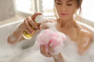Duş jeli döken güzel bir kadın. Kapalı alanda banyo yapıyor, ellere odaklanıyor.