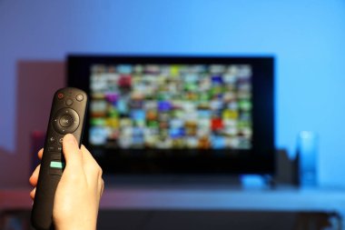 Televizyonda uzaktan kumandayla kanal değiştiren bir kadın. Metin için boşluk