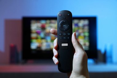 Televizyonda uzaktan kumandayla kanal değiştiren kadın, yakın çekim.