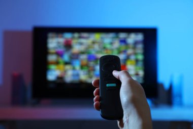Televizyonda uzaktan kumandayla kanal değiştiren kadın, yakın çekim.