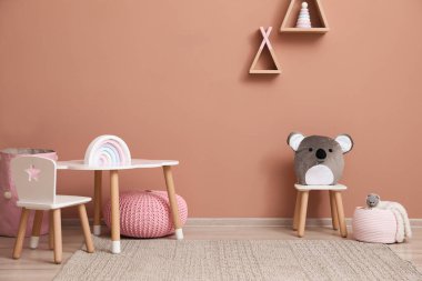 Mobilyaları, oyuncakları ve pembe duvarları olan şirin bir çocuk odası.