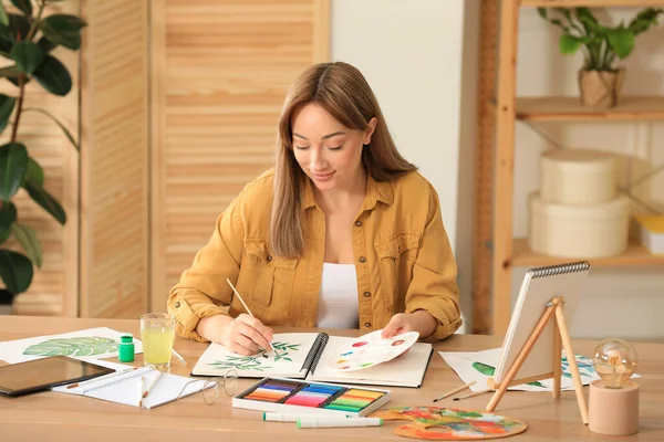 Jonge Vrouw Schilderen Groene Takje Schetsboek Aan Houten Tafel Binnen — Stockfoto