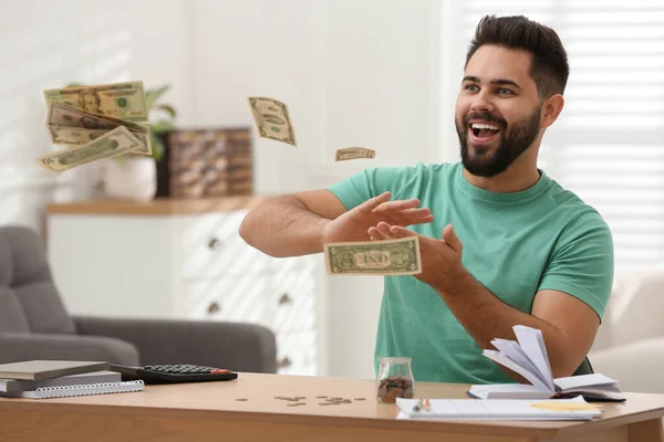 Glücklicher Junger Mann Wirft Geld Auf Holztisch Haus — Stockfoto