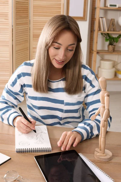 女性は屋内の木製のテーブルでペンでスケッチブックで描く — ストック写真