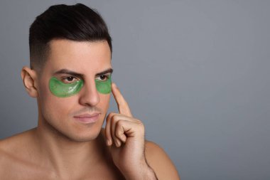 Gri arka plana yeşil göz bandı takan bir adam. Metin için boşluk