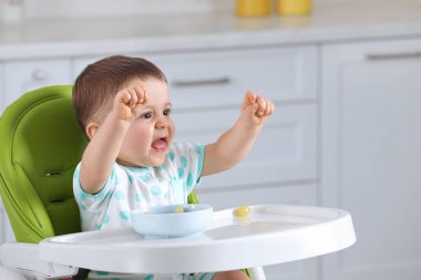 Evdeki yüksek sandalyede sağlıklı yiyecekler yiyen şirin bir bebek. Mesaj atmak için yer var.