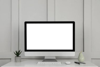 Modern bilgisayar, dekor ve ofis malzemeleri, pervazların yanındaki beyaz ahşap masada.