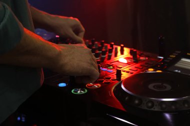 DJ, gece kulübünde modern konsol karıştırıcısında müzik yaratıyor.