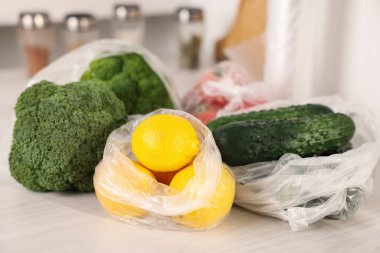 Plastik torbalar ve beyaz masada taze ürünler.