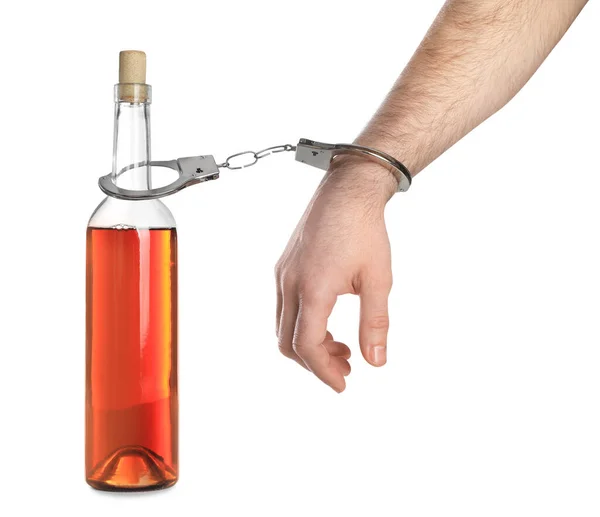 白い背景にアルコール飲料のボトルと手錠で中毒の男 クローズアップ — ストック写真