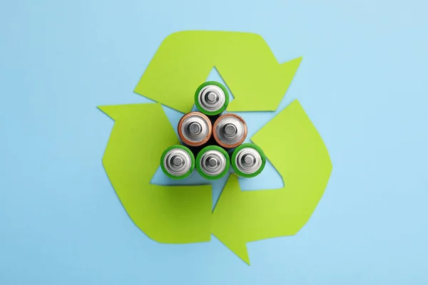 ライトブルーの背景に使用されるバッテリーとリサイクルシンボル フラットレイ — ストック写真