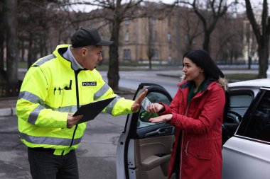 Polis memuru dışarıda arabanın yanında rüşvet vermeyi reddediyor.