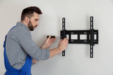 Uzman teknisyen tornavidayla duvara televizyon desteği yerleştiriyor.