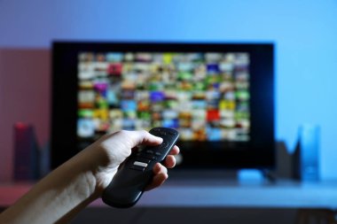 Televizyonda uzaktan kumandayla kanal değiştiren kadın, yakın çekim.
