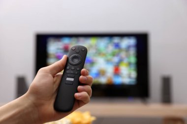 Televizyonda uzaktan kumandayla kanal değiştiren bir kadın. Metin için boşluk