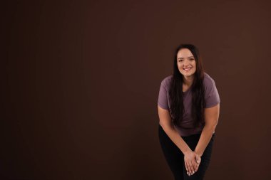 Kahverengi arka planda sevimli gülüşü olan şişman, güzel bir kadın. Metin için boşluk