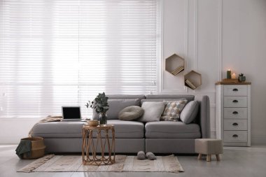 Rahat gri kanepeli oturma odası ve pencerenin yanındaki iç dekorasyonlar.