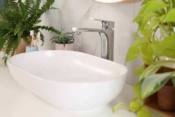 浴室柜台 白色大理石墙边有水池 漂亮的绿色室内植物和牙刷 — 图库照片
