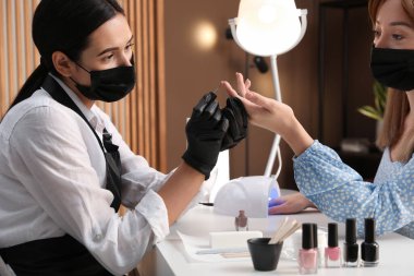 Müşteriyle kuaförde çalışan profesyonel bir manikürcü. Coronavirus karantinası sırasında güzellik hizmetleri