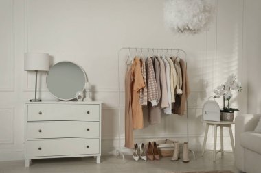 Modern giyinme odası. Şık kıyafetler, ayakkabılar ve güzel orkide çiçekleri.