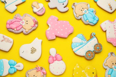 Sarı arka planda farklı şekillerde tatlı kurabiyeler, düz yatış. Bebek partisi.