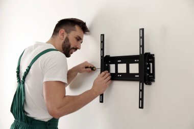 Uzman teknisyen tornavidayla duvara televizyon desteği yerleştiriyor.