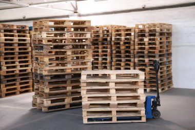 Modern manuel forklift ve ahşap paletler depoda.