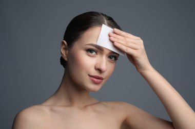 Gri arka planda matlaştırıcı mendil kullanan güzel kadın