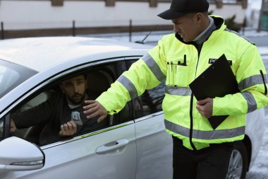 Polis memuru dışarıda arabanın yanında rüşvet vermeyi reddediyor.