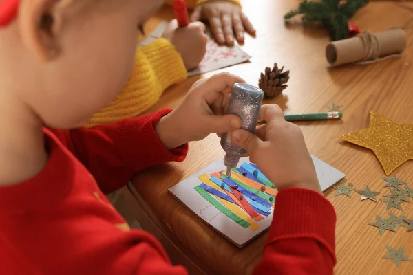 Lindo Niño Pequeño Haciendo Hermosa Tarjeta Felicitación Navidad Mesa Madera — Foto de Stock