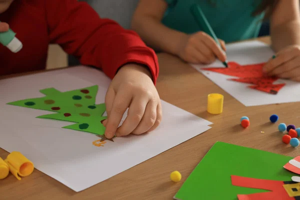 木製のテーブルで美しいクリスマスのグリーティングカードを作っている小さな子供たち クローズアップ — ストック写真