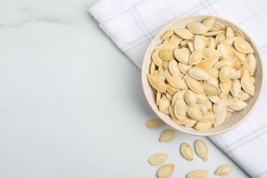 Beyaz masanın üzerinde bal kabağı tohumları olan bir kâse. Metin için boşluk