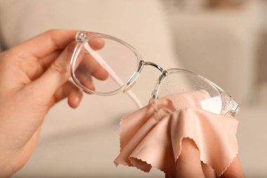 Kadın evde mikrofiber bezle bardakları temizliyor, yakın plan.