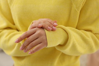 Yumuşak sarı kumaştan yapılmış kazağa dokunan kadın, yakın plan.