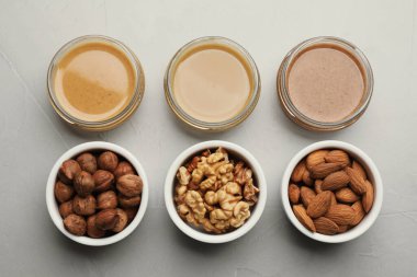 Farklı türde lezzetli fındık ezmesi ve malzemeler gri masada, düz yerde.