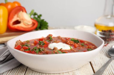 Beyaz ahşap masada bir kase lezzetli doldurulmuş biber çorbası.