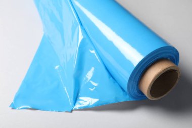 Beyaz arkaplanda plastik germe filminin rulosu, yakın plan