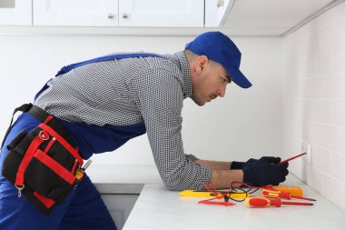 Elektrikçi elektrik prizine kapalı tamir tornavida ile