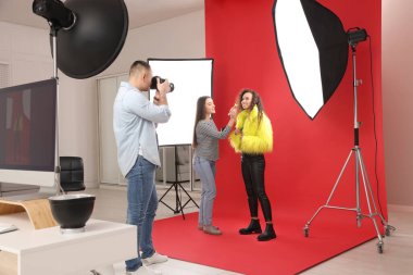 Stüdyoda model olan profesyonel fotoğrafçı ve makyöz.