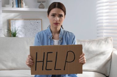 Mutsuz, genç bir kadın. Kapalı koltukta yardım yazısı var.